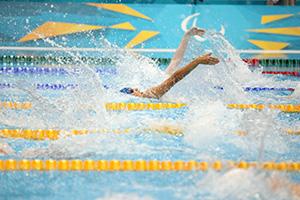 Kuvassa Antti Latikka ui kilpaa altaassa, hänestä näkyy vain vähän kasvoja ja toinen käsivarsi.