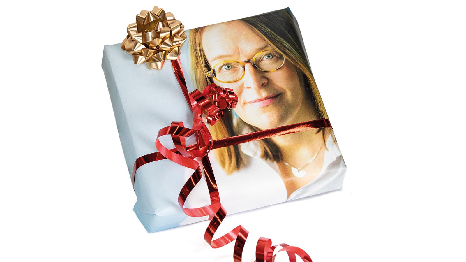 Valokuva joululahjapaketista, jonka käärepaperina on käytetty Marika Mäkisen normaalisti Näkövammaisten Airuen pääkirjoitussivulla näkyvää valokuvaa.