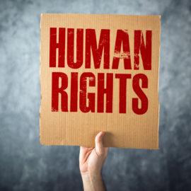 Kuvassa Käsi pitää kylttiä, jossa lukee Human rights
