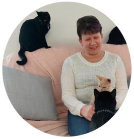 Kirsi Tolonen sohvalla neljän kissan kanssa.