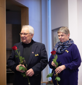 Mies ja nainen ruusut käsissään ja ansiomerkki rinnassaan.